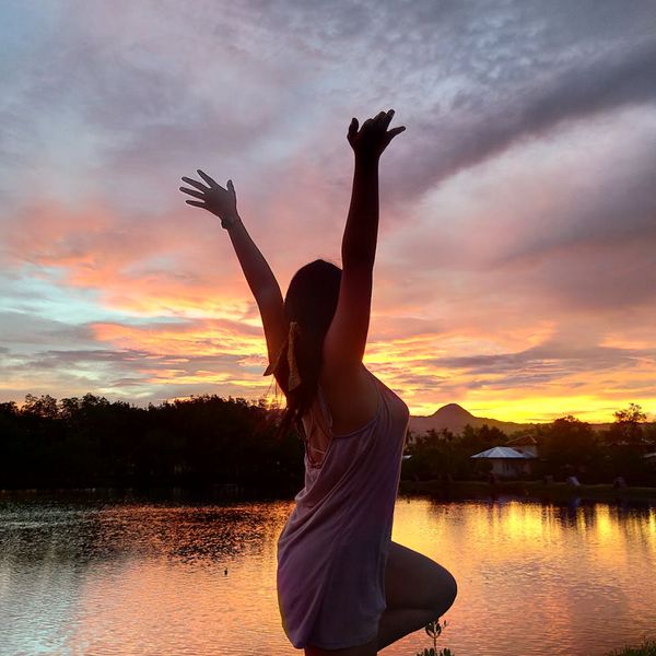 Silhouette of a person in a yoga pose against a calm background.